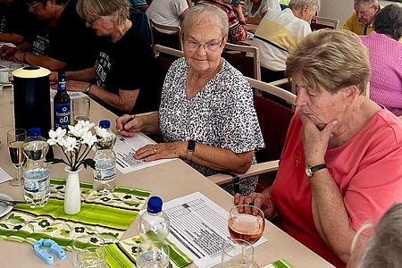Rätsel und Geschicklichkeit bei der Seniorenolympiade Zwei Seniorinnen sitzen über einem Fragebogen und überlegen.