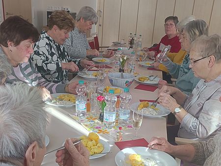 Kaffeenachmittag mit Heringssalat mehrere Semiorinnen sitzen an einer Tafel und Essen Heringssalat mit Kartoffeln