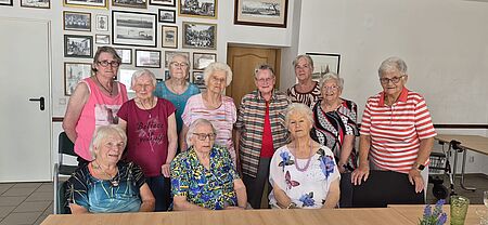 Im Bürgerhaus "Zur Sonne" treffen sich die Seniorengruppen von Seehausen zu Kaffeenachmittagen Drei Seniorinnen sitzen an einer Tafel. Dahinter stehen weitere acht Seniorinnen und schauen in die Kamera