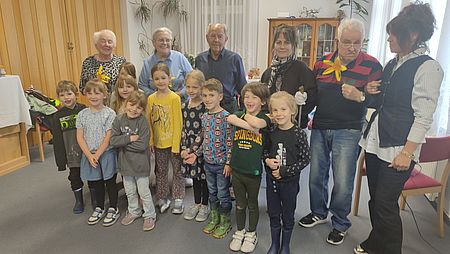 Kita-Kinder gratulieren den Jubilaren eine Gruppe Kita-Kinder stehen vor vier Senioren mit Blumensträußen