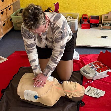 Die Mitarbeiter der Kita "Sarrezwerge" haben eine besonder Weiterbildung absolviert Eine Frau reanimiert ein Übungsmodell mit angeschlossenem Laiendefibrillator