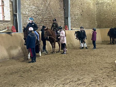 In der Reithalle konnten die Kinder ihr Können verbessern Mehrere Kinder auf und neben Pferden in einer Reithalle