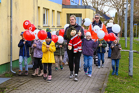Kinder der Kita "Sarrezwerge" tragen die DRK Fackel Kinder mit Luftballons tragen eine Fackel