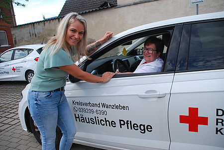 Pflegedienstleiterin Carolin Klose (li) und Marion Stach sind für den DRK-Kreisverband seit langen Jahren in Eillseben tätig Eine Frau lehnt an einer Autotür. Eine andere Frau sitzt am steuer eines DRK Fahrzeugs