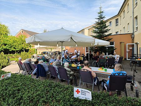 Grillfest im "Rusches Hof" Senioren sitzen unter Sonnenschirmen an zwei Kaffeetafeln im Freien