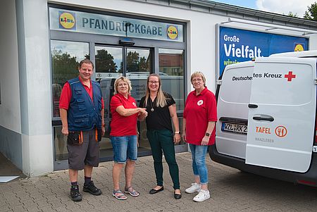 Die Tafeln in Wanzleben erhalten eine Spende aus Pfandeinnahmen durch Lidl Drei Frauen und ein Mann stehen vor der Lidl-Pfandstation und reichen sich die Hände