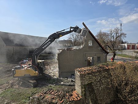 Abriss eines alten Wohnhauses Ein Bagger greift in den halb abgerissenen Giebel eines Wohnhauses